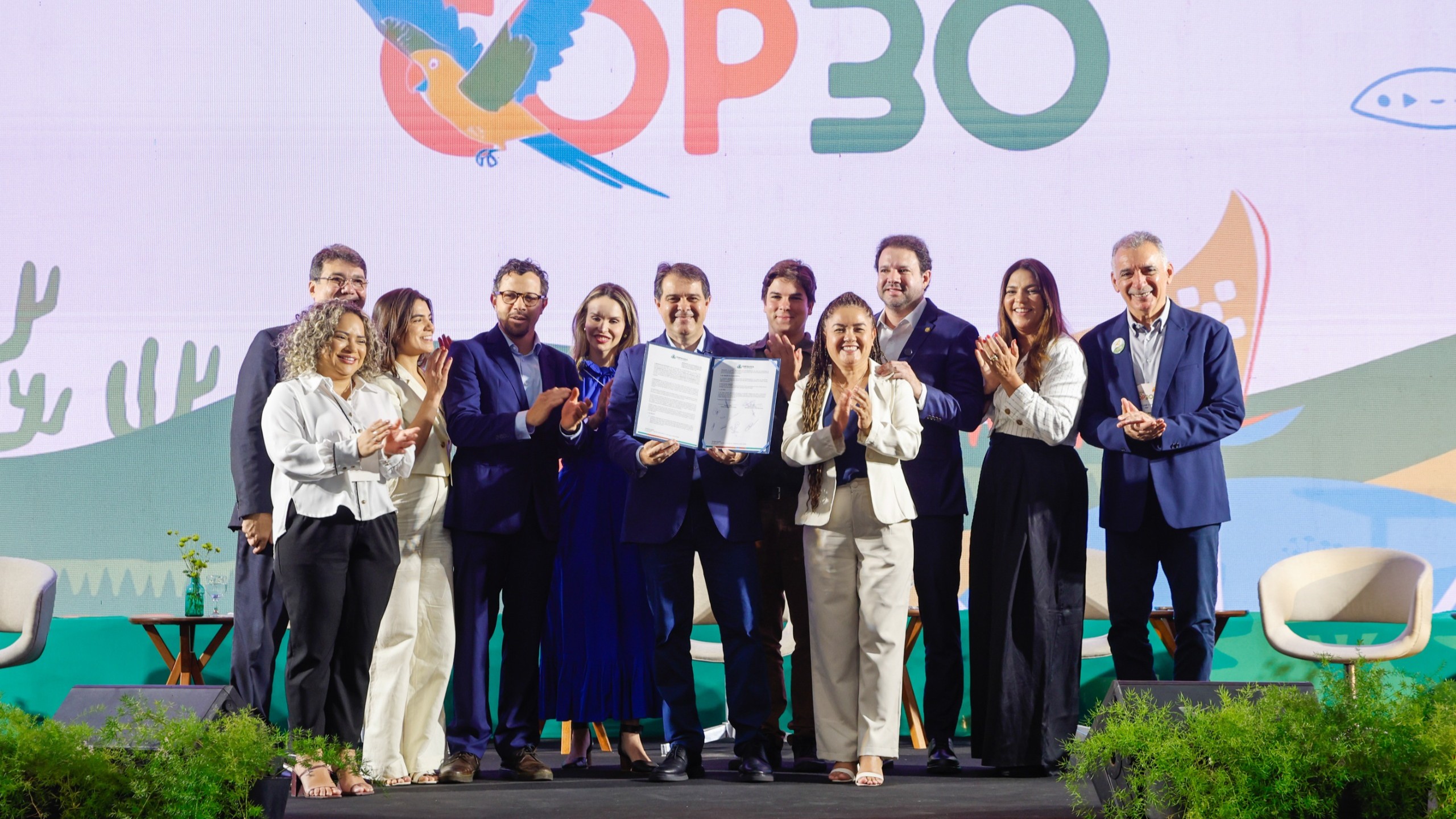 grupo de pessoas posa para a foto no palco do centro de eventos